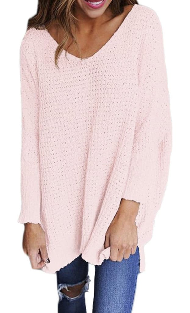 A model wearing a light, oversized pink knitted sweatshirt and blue jeans.