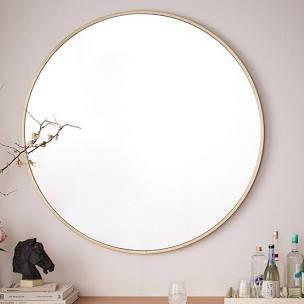 A large round oversized mirror with a thin gold frame from West Elm.