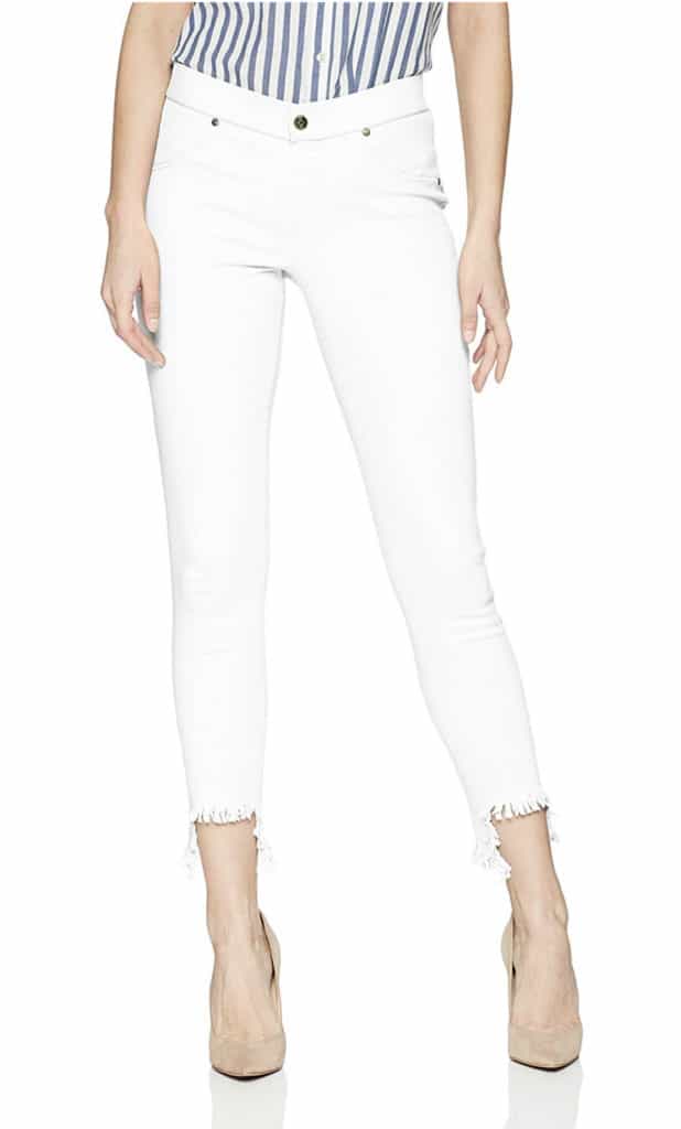 A model wearing white skinny jeans with a distressed ankle-length hem paired with nude high heels.