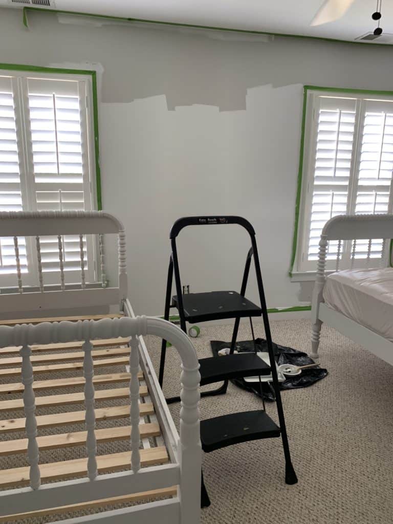Painting the shared boy and girl bedroom with an eggshell white paint during the shared bedroom makeover.