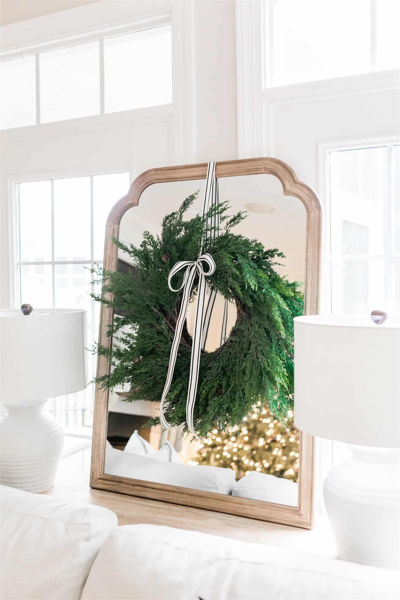 How to decorate your mantel for Christmas with simple garland, black and white striped ribbon, bells, and neutral stockings. Also, a look at our Christmas decor from last year. A simple and neutral Christmas decor inspiration post. #neutralchristmas #christmasdecor #simplechristmas #christmasinspiration #cedargarland
