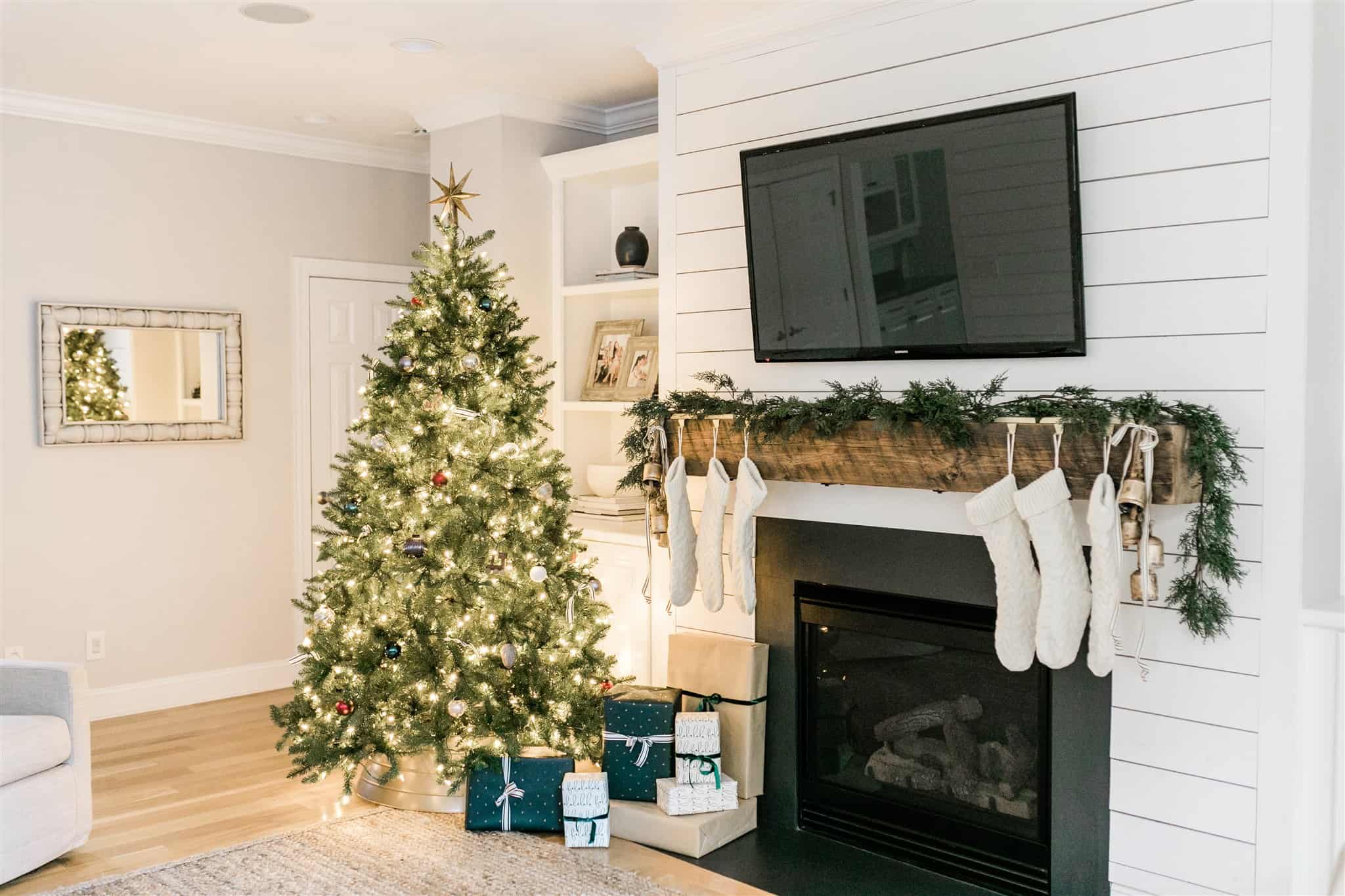 How to decorate your mantel for Christmas with simple garland, black and white striped ribbon, bells, and neutral stockings. Also, a look at our Christmas decor from last year. A simple and neutral Christmas decor inspiration post. #neutralchristmas #christmasdecor #simplechristmas #christmasinspiration #cedargarland