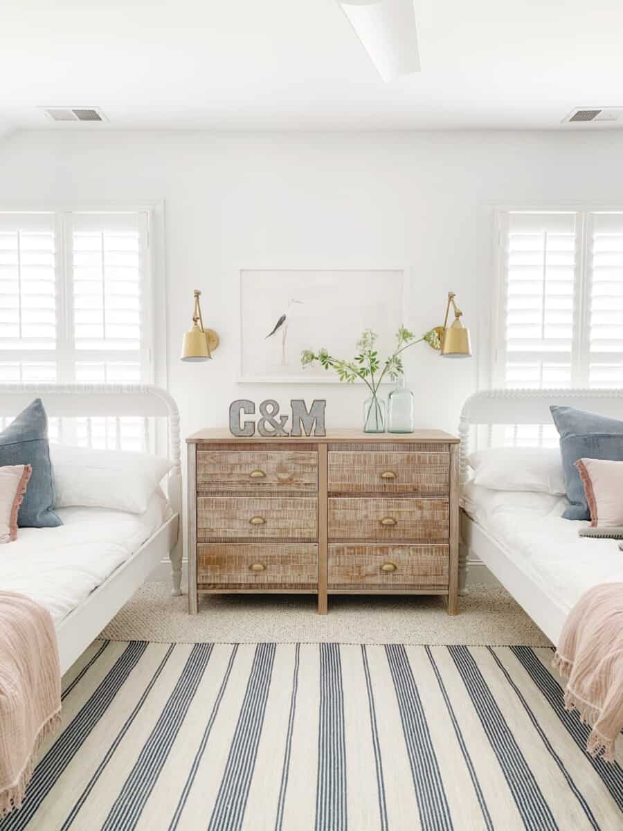 A white-framed pelican print hangs over the dresser that sits between the twin beds in our kids' bedroom. #coastalart #coastal #artprints #kidsroom #kidsdecor #coastalkidsroom #beachhouse #beachdecor #sailboatnursery #coastalnursery