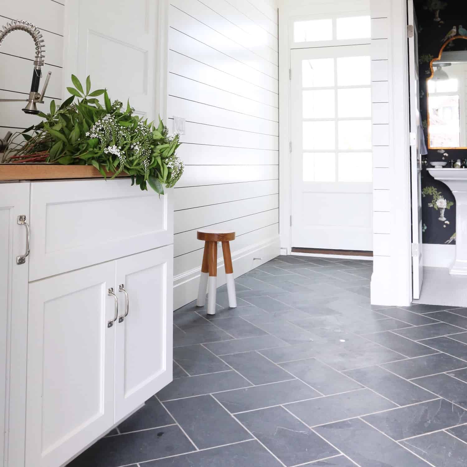 Gorgeous dark tile flooring and shiplap walls are inspiration for our upcoming laundry room makeover.#butcherblock #paintedfloors #paintedtilefloors #coastalhome #coastaldecor #coastallaundryroom #laundryroomfloors #slatetile #verticalshiplap #vintagedecor #vintagerug #laundryroomrug