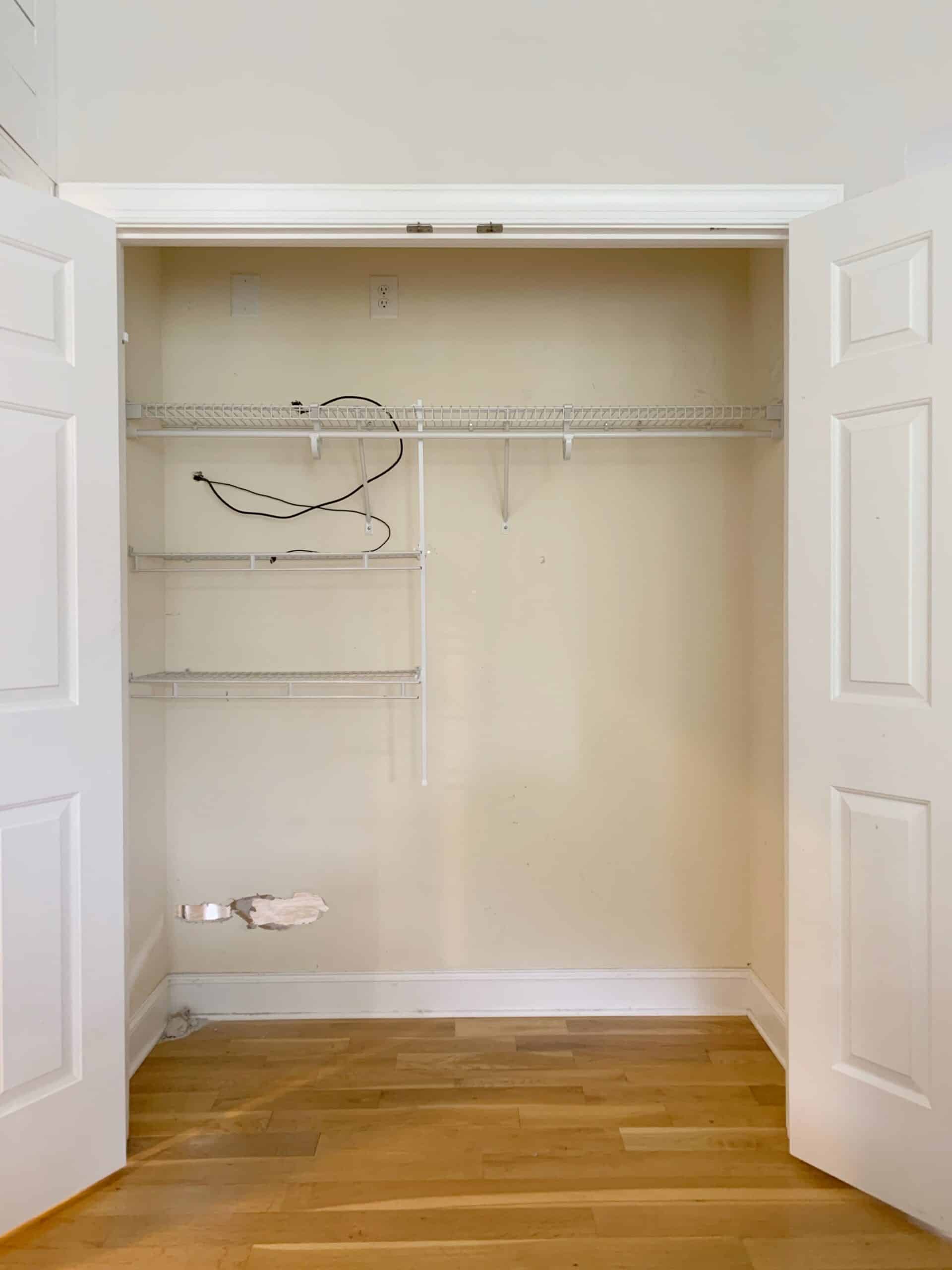 The empty walk-in closet doors stand open, reveling empty wire racks and shelves which will soon be replaced with Closets By Liberty closet organizing systems.