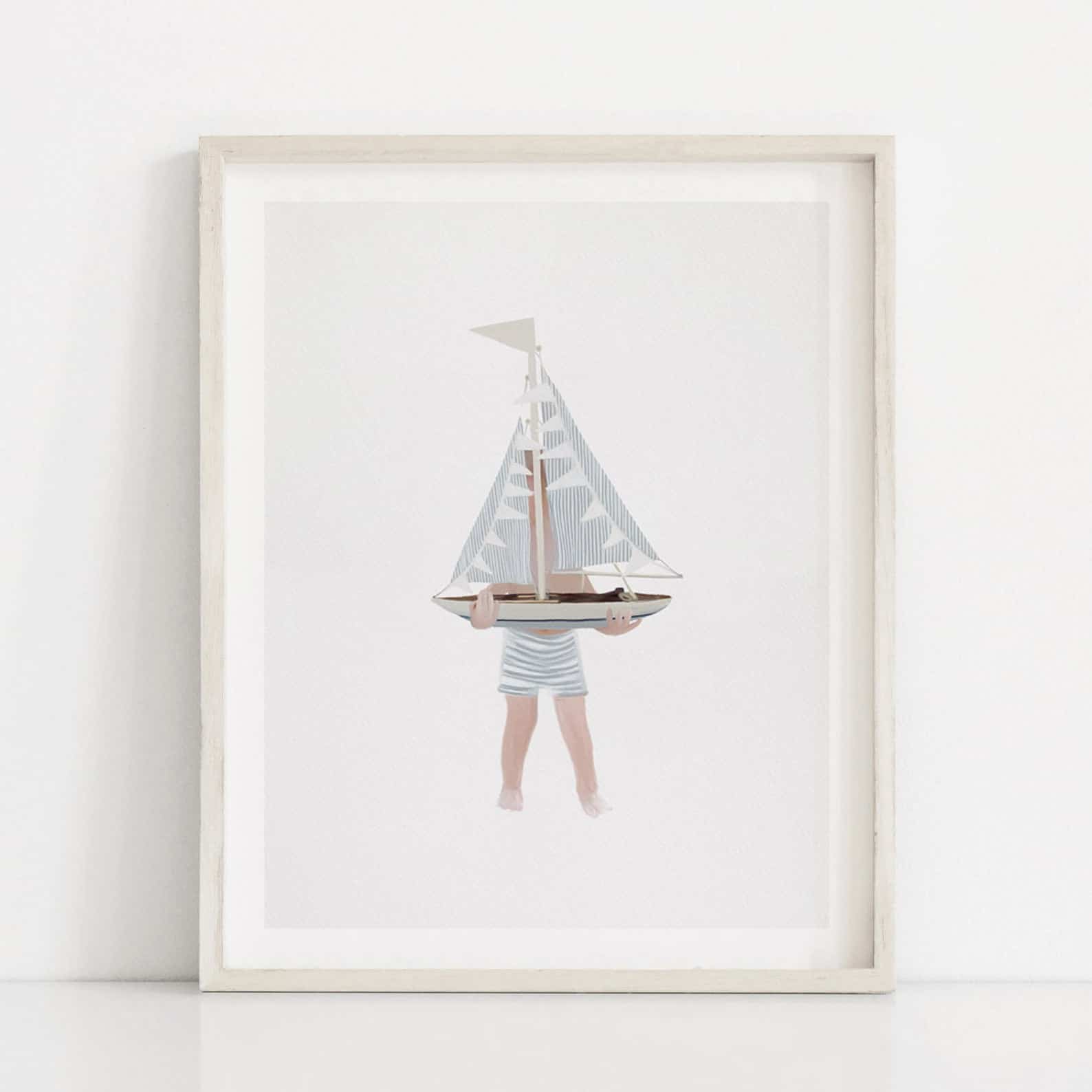 this kid-friendly coastal art print features a drawing of a young child holding a toy sailboat, against a white background and framed with a whitewashed wood frame.