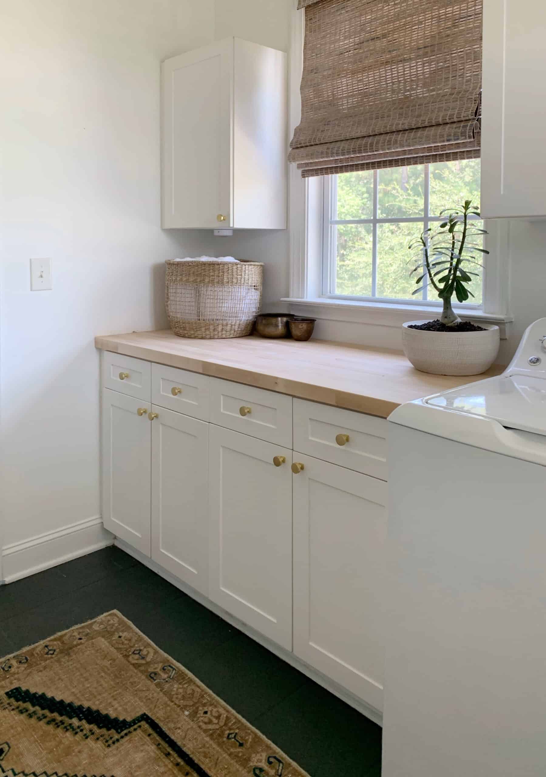 How to seal your new butcher block countertop with a natural finish - a finished look at the new butcher block counter top in the laundry room #laundryroom #butcherblock #butcherblockcountertop #countertop #diycounters #coastalhome #coastallaundryroom #vintageruglaundryroom #vintagerug #paintedtile #paintedfloors