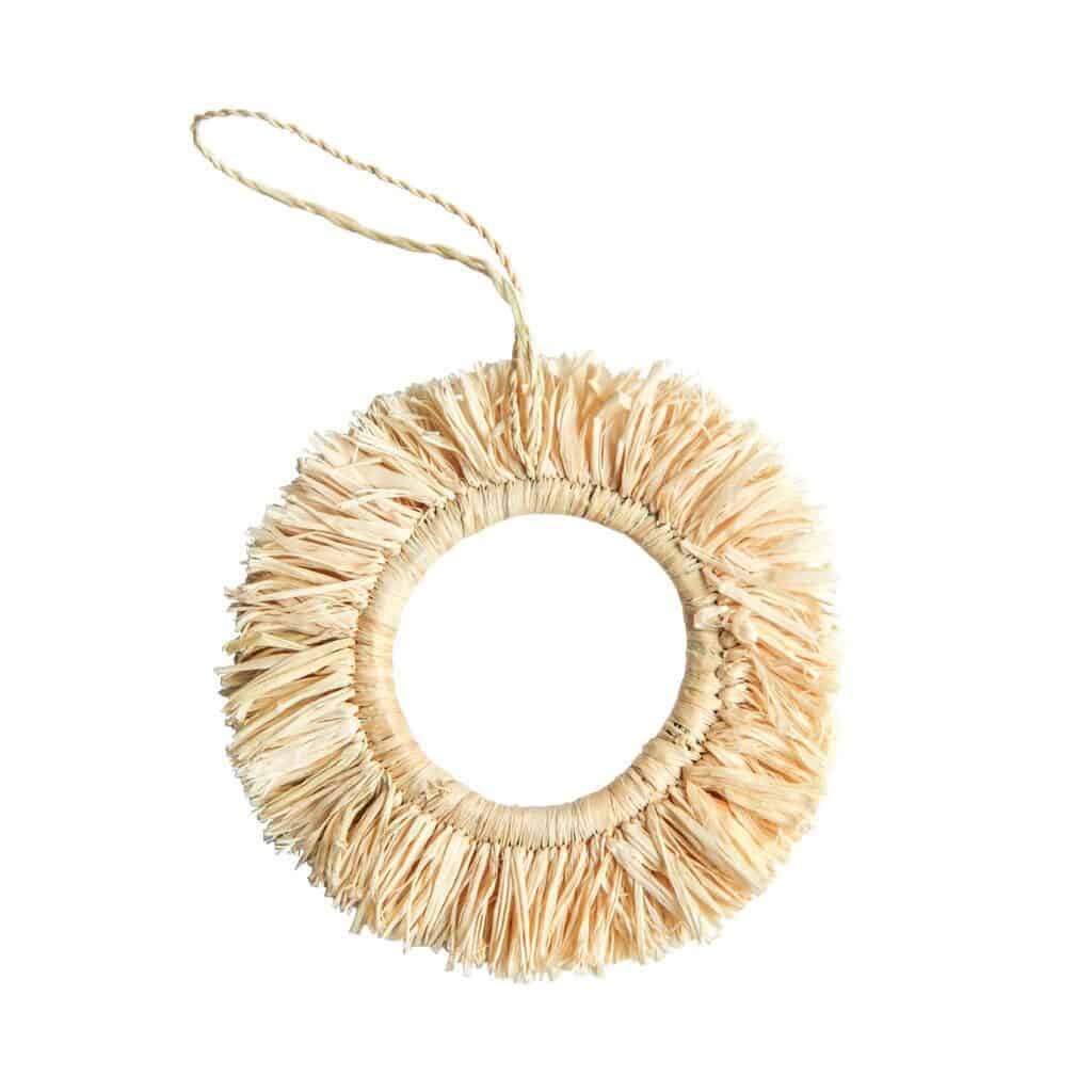 A simple tasseled fabric ring ornament in a light cream color.