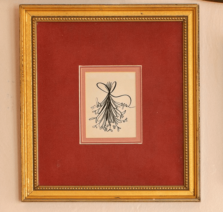 A white and gold framed print of an abstract Christmas tree drawing.