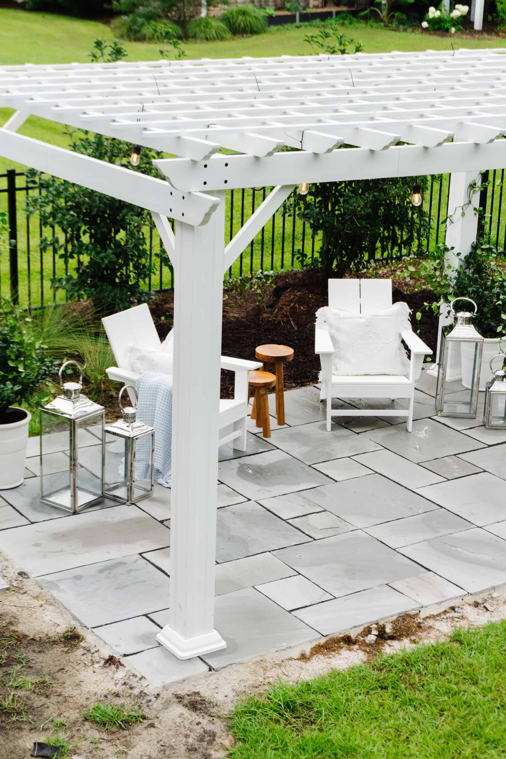Patio with white pergola and two Adirondack chairs.