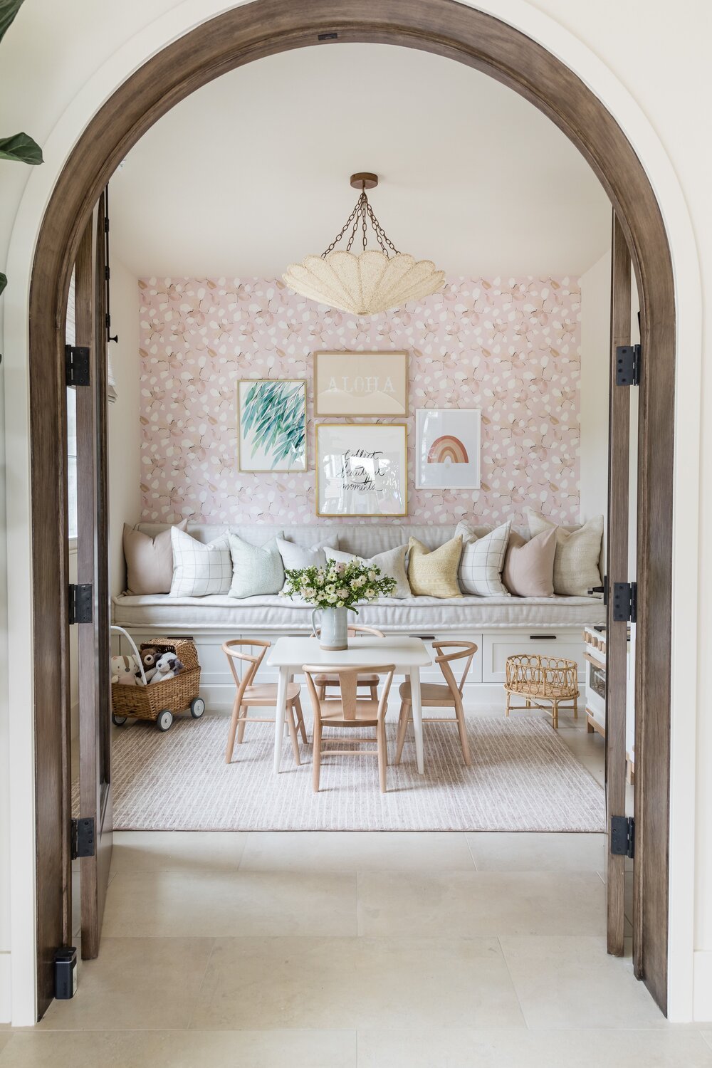 Playroom design with floral wallpaper, bench, and kids table with toys.