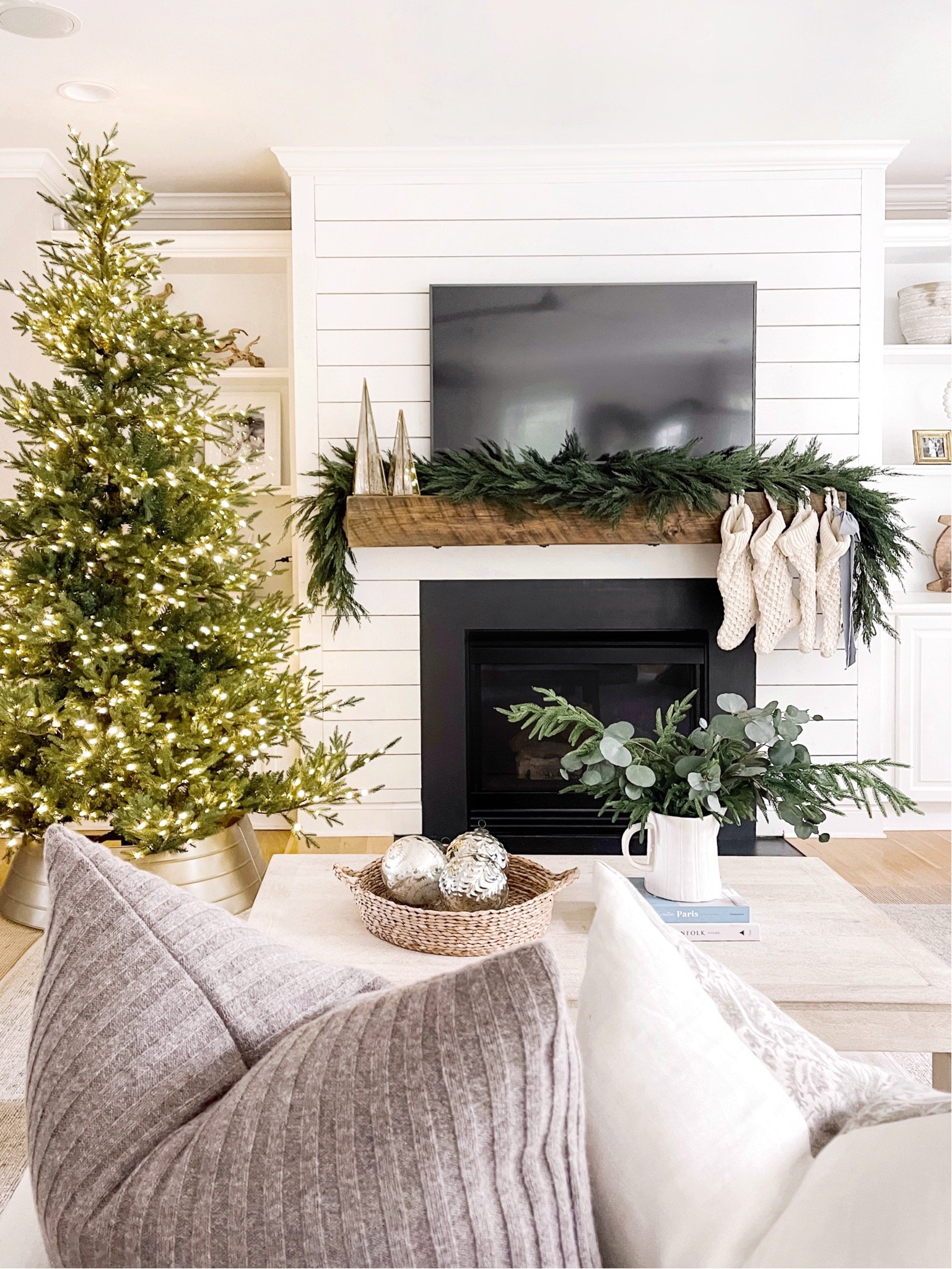 Living room decor with coffee table styling and fireplace decorated with green garland for christmas.